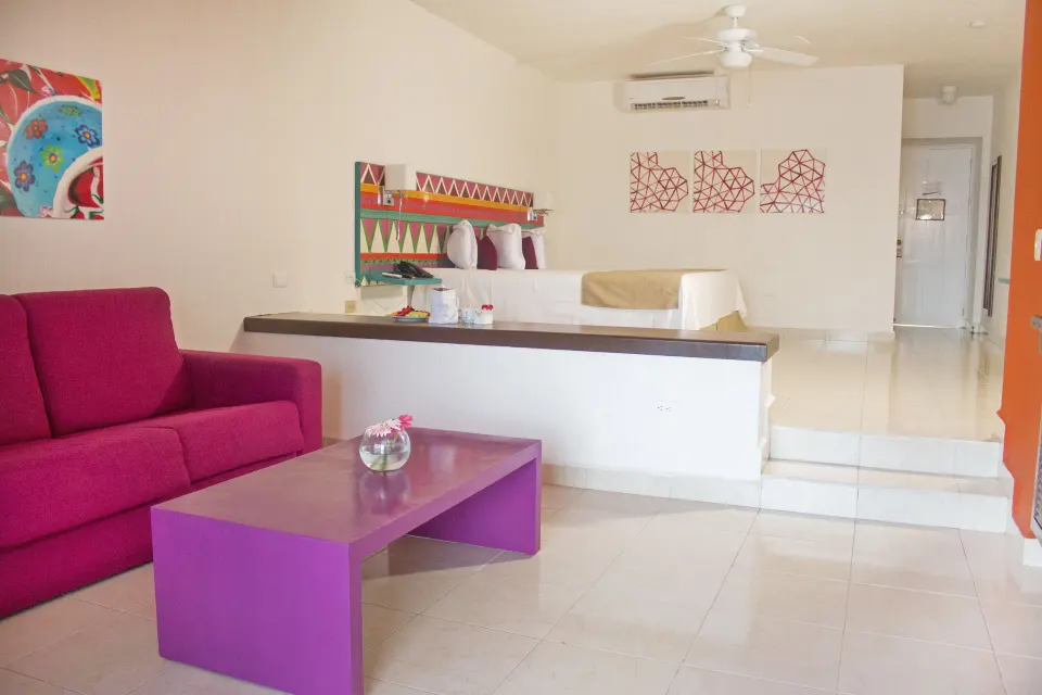 Junior Suite Sea View split-level room with red sofa at All Ritmo Cancun Resort & Water Park.