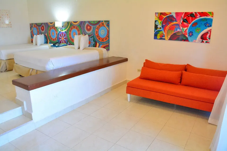 Junior Suite Sea View room with two beds and orange sofa at All Ritmo Cancun Resort & Water Park.