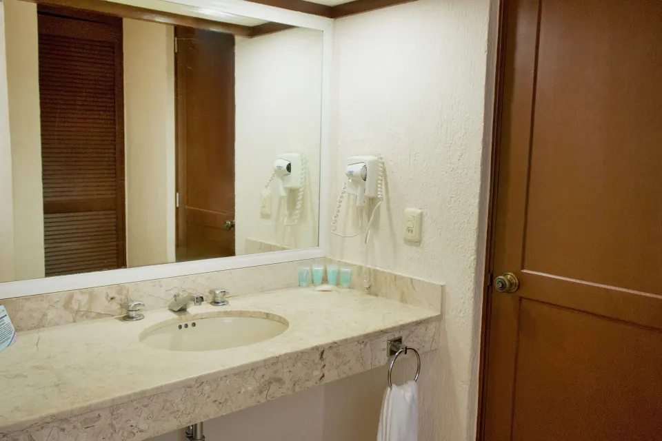 Standard room bathroom sink with mirror at All Ritmo Cancun Resort & Water Park.