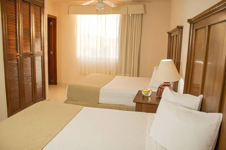 Standard room with two beds and louvered closet doors at All Ritmo Cancun Resort & Water Park.