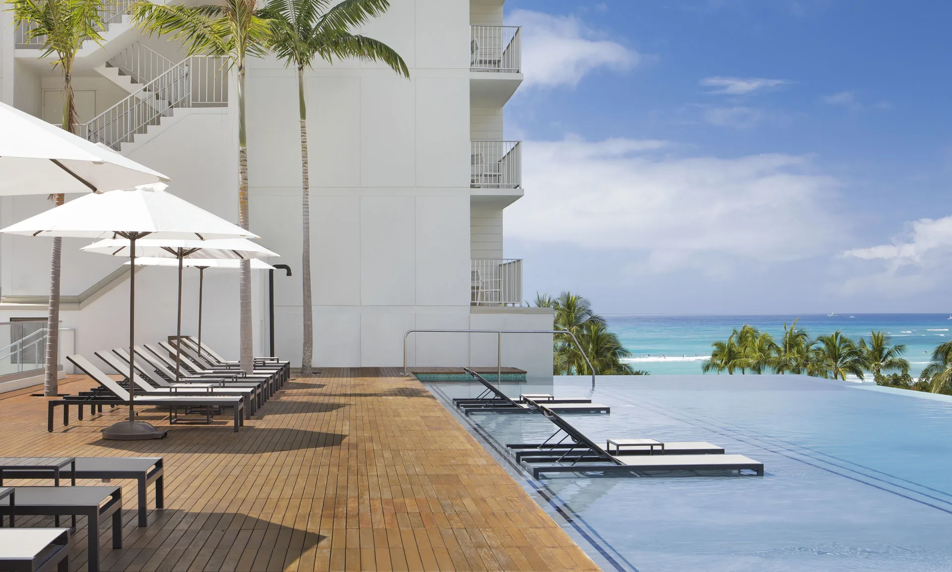 Infinity pool deck with loungers and ocean view at 'Alohilani Resort Waikiki Beach.