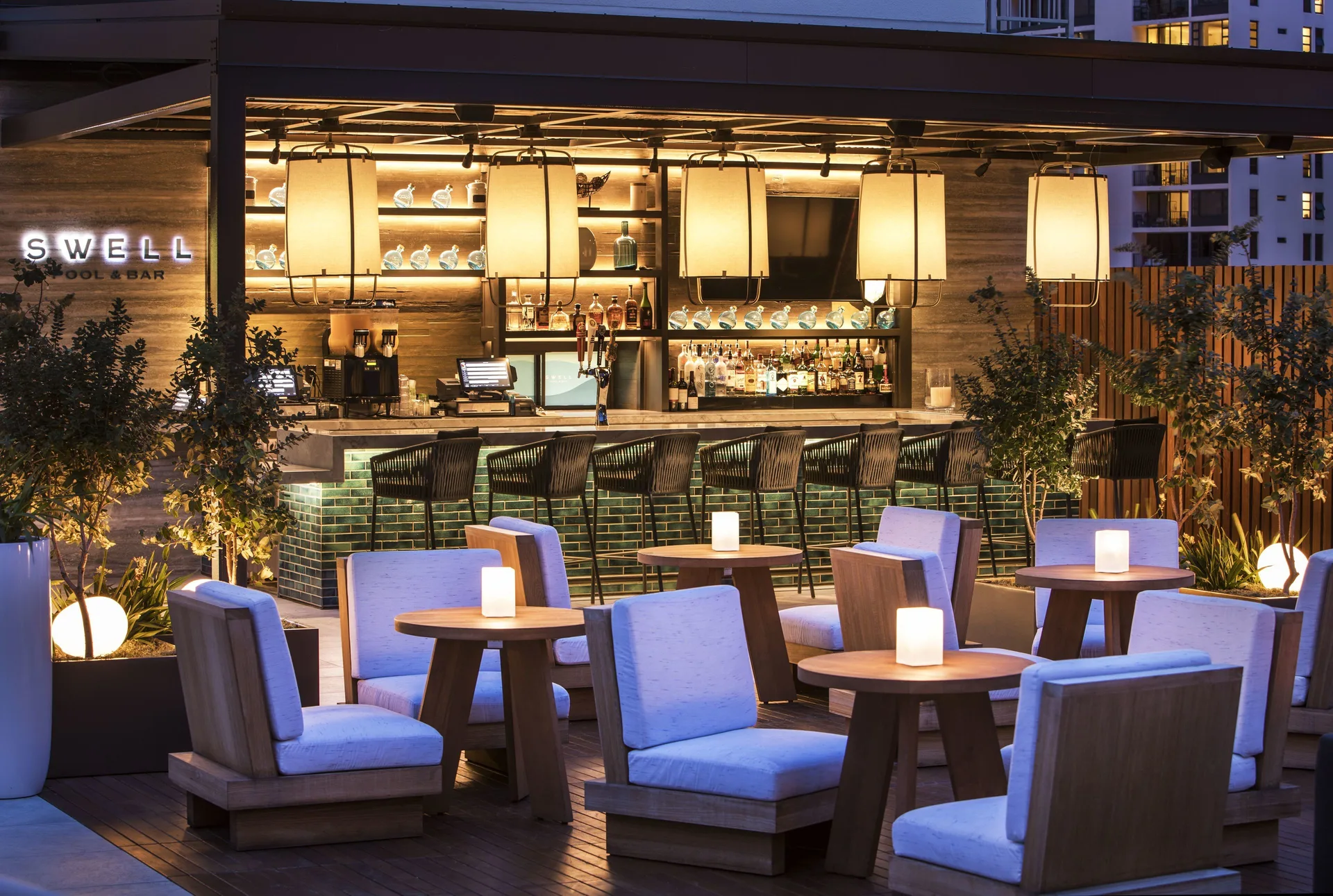 SWELL pool bar with lounge seating at dusk at 'Alohilani Resort Waikiki Beach.