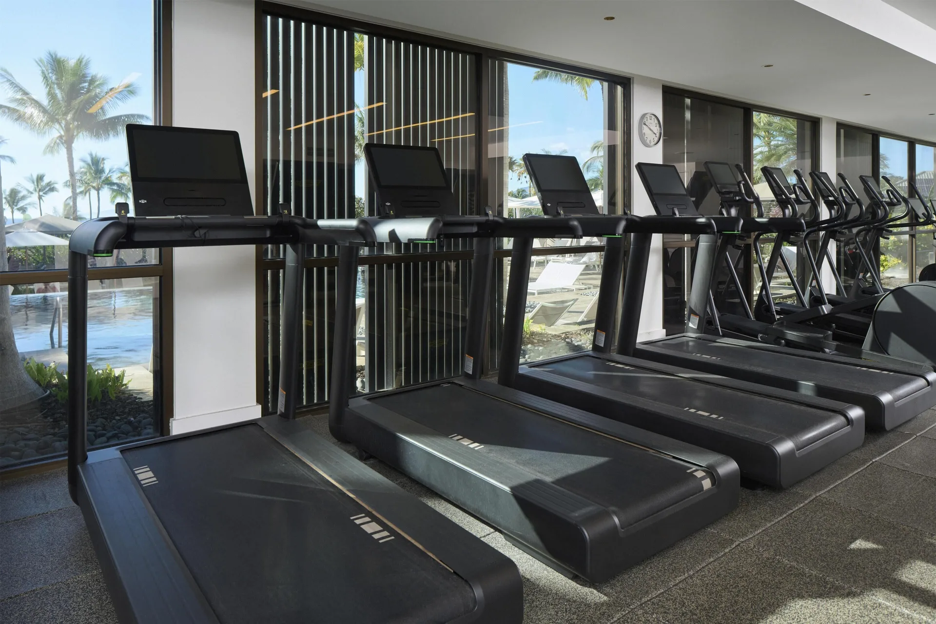 Treadmills facing windows with poolside views at Andaz Maui at Wailea Resort.