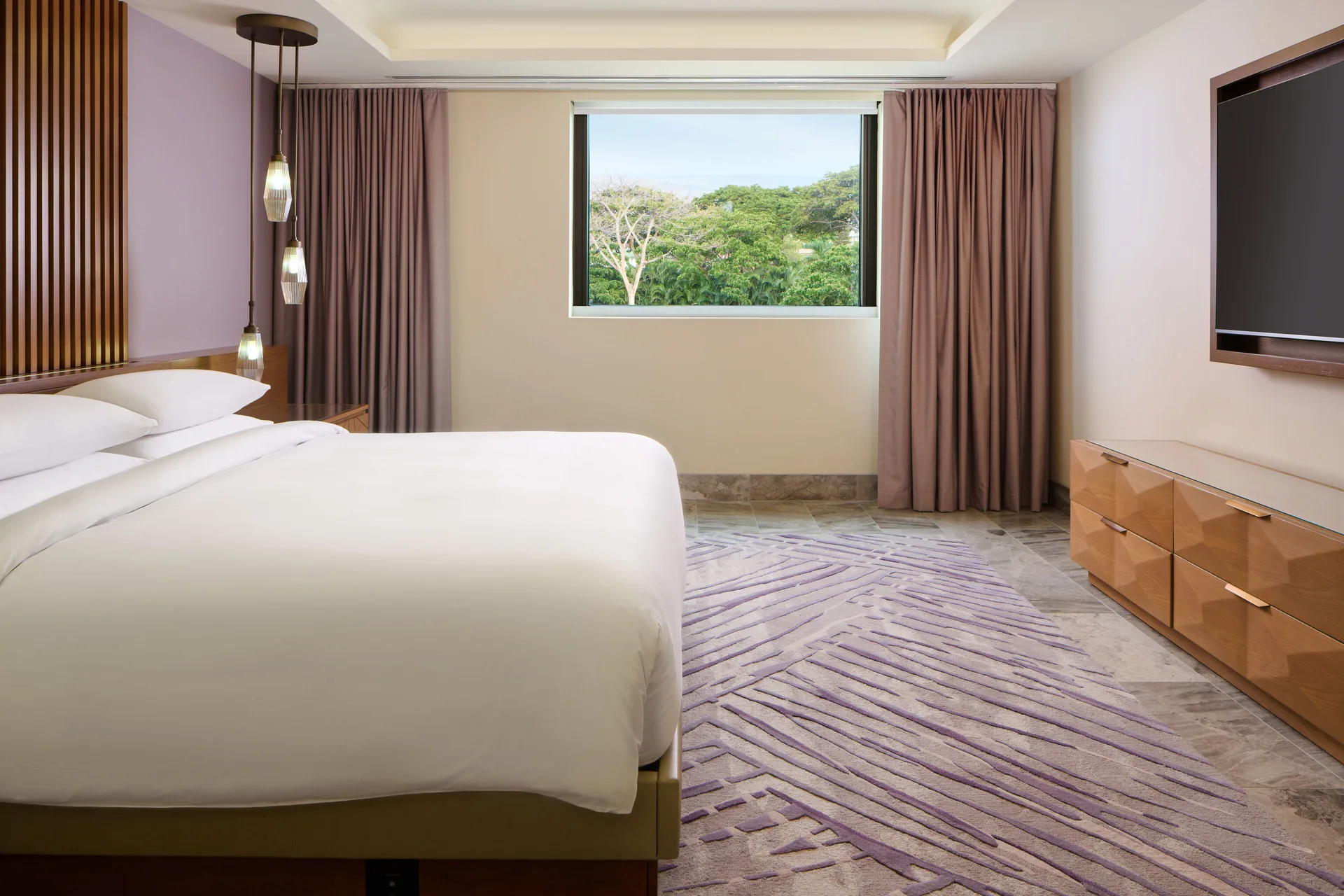 Guest room king bed with window greenery and wall-mounted TV at Andaz Maui at Wailea Resort.