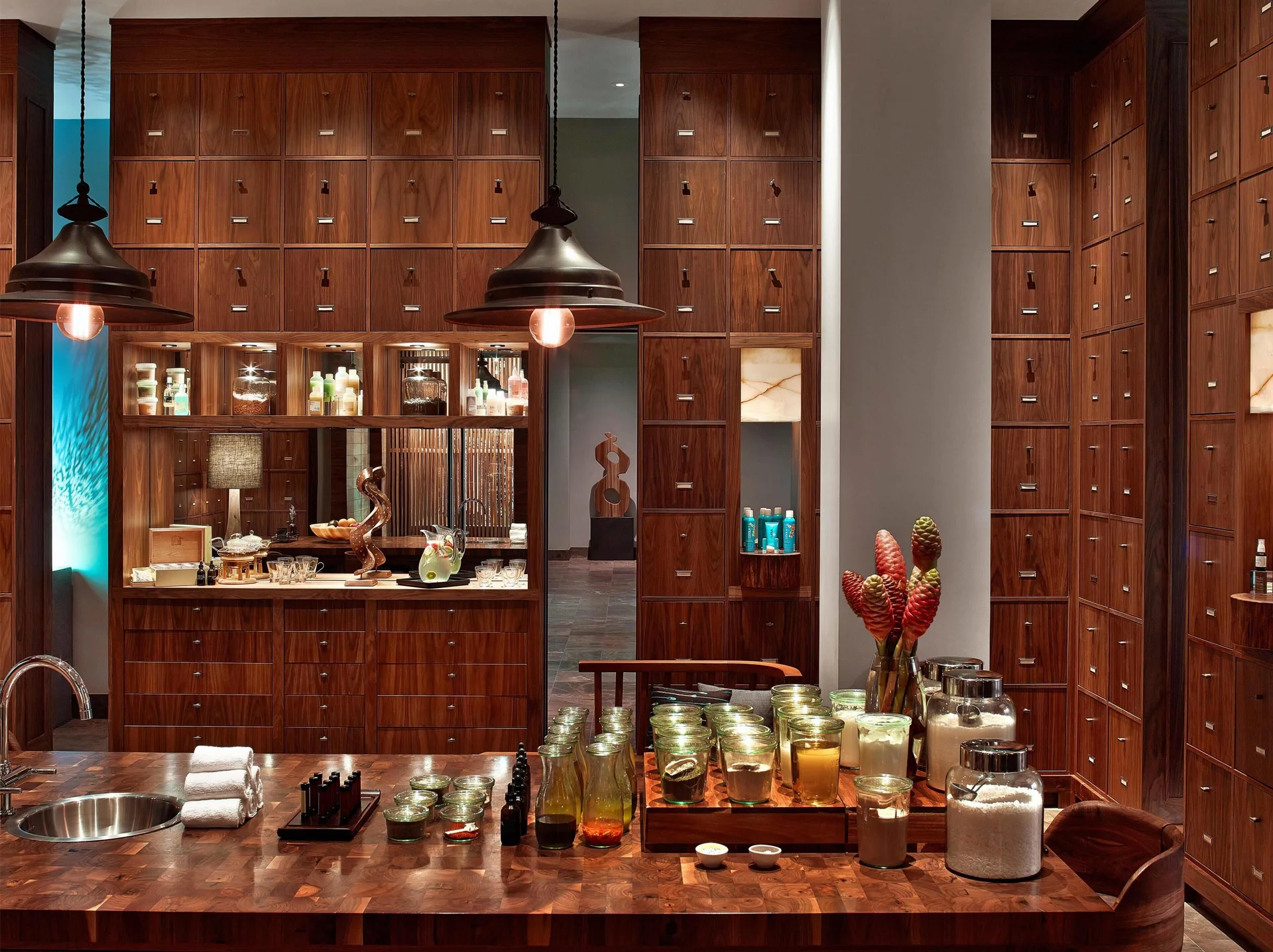 Spa apothecary counter with jars, candles, and wood cabinetry at Andaz Maui at Wailea Resort.