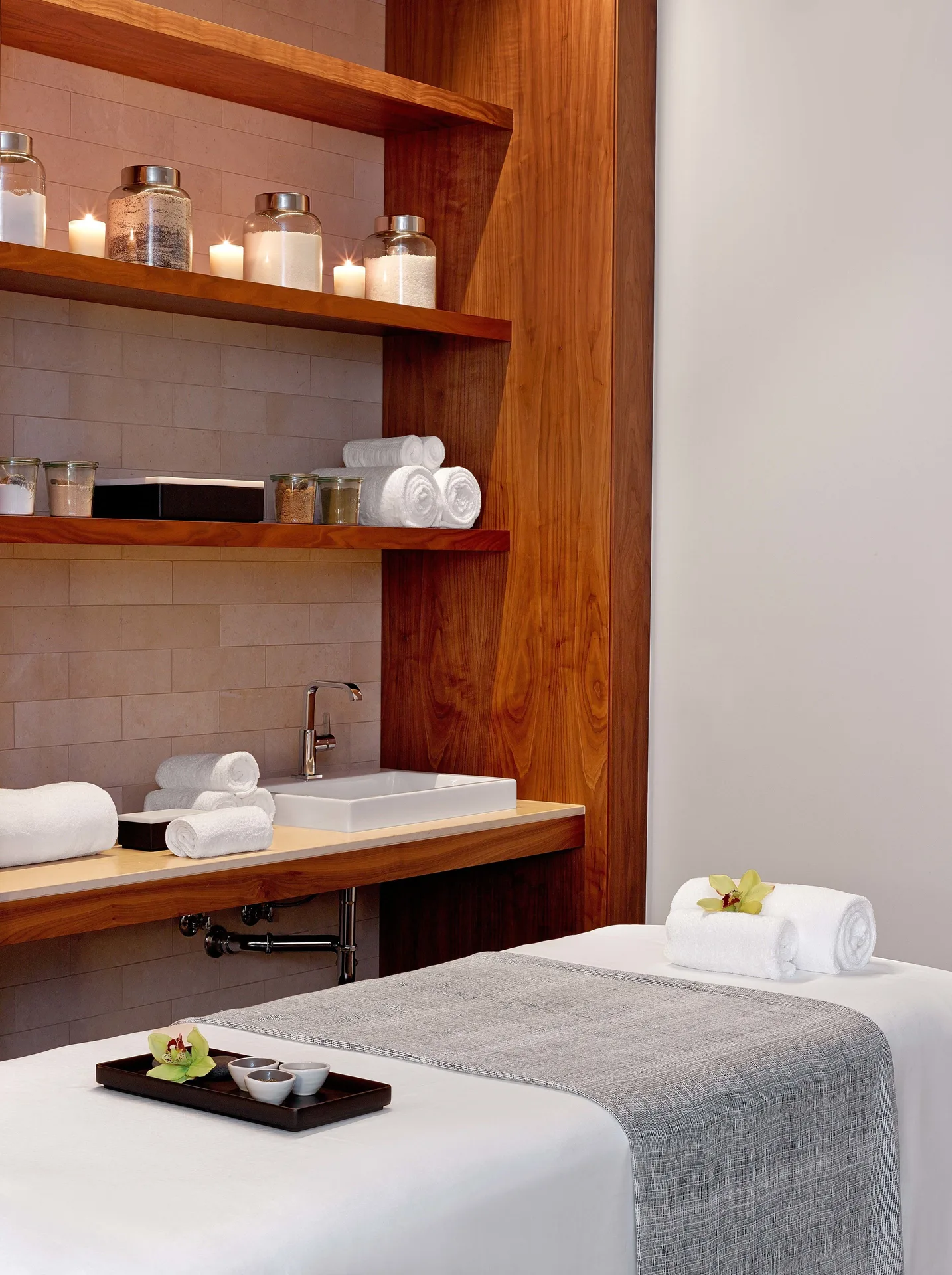 Spa treatment room with massage tables and wood shelving at Andaz Maui at Wailea Resort.