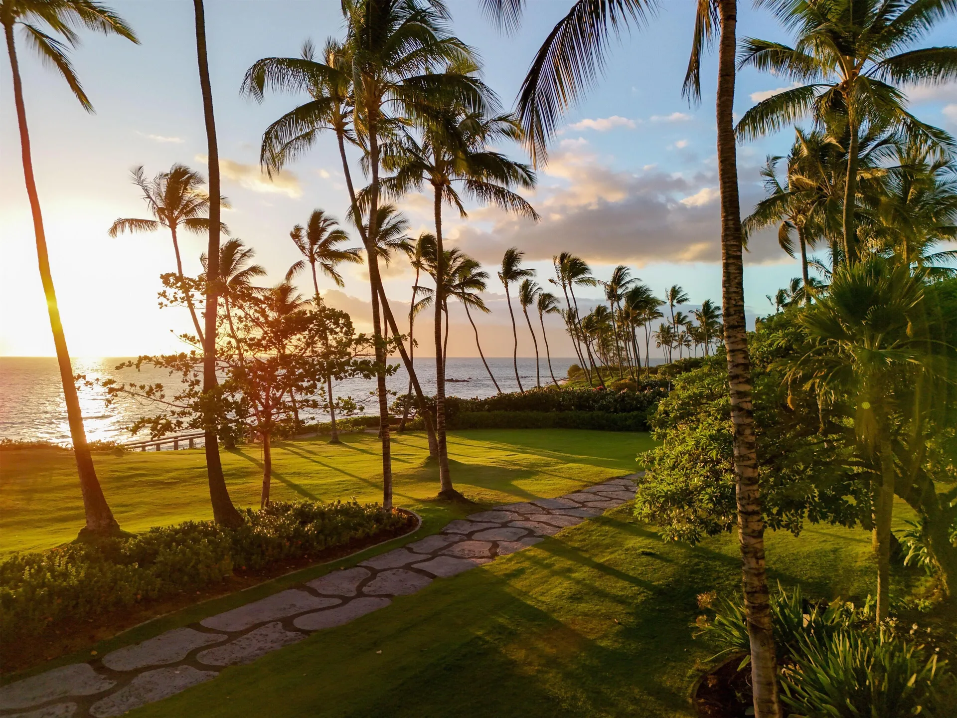 Sunset over palm-lined oceanfront grounds at Andaz Maui at Wailea Resort.