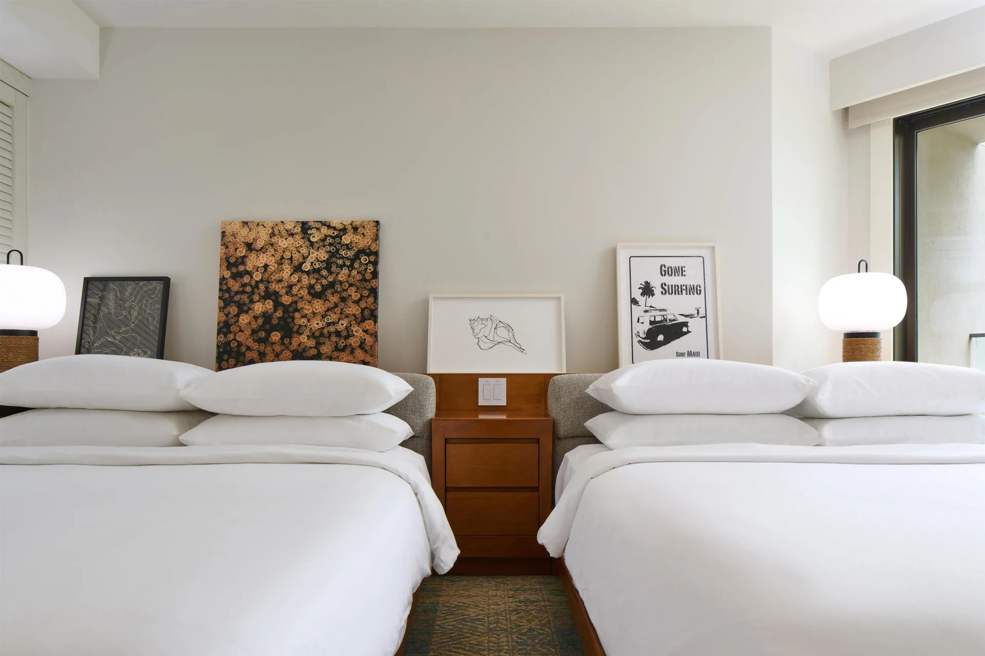 Two queen beds with wall art and bedside lamps in a resort view room at Andaz Maui at Wailea Resort.