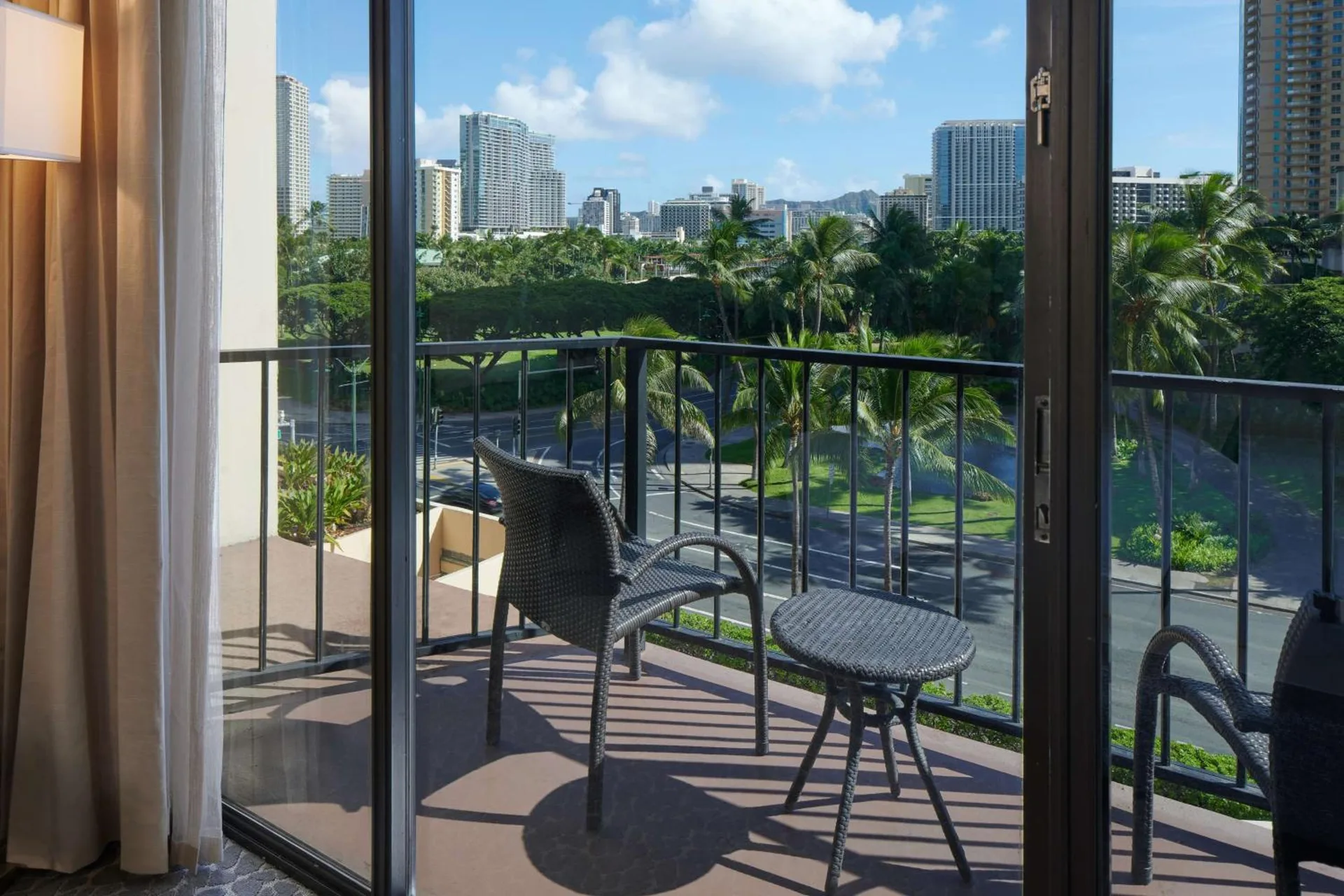 Balcony seating with palm trees and Waikiki buildings viewed from Aqua Palms Waikiki.
