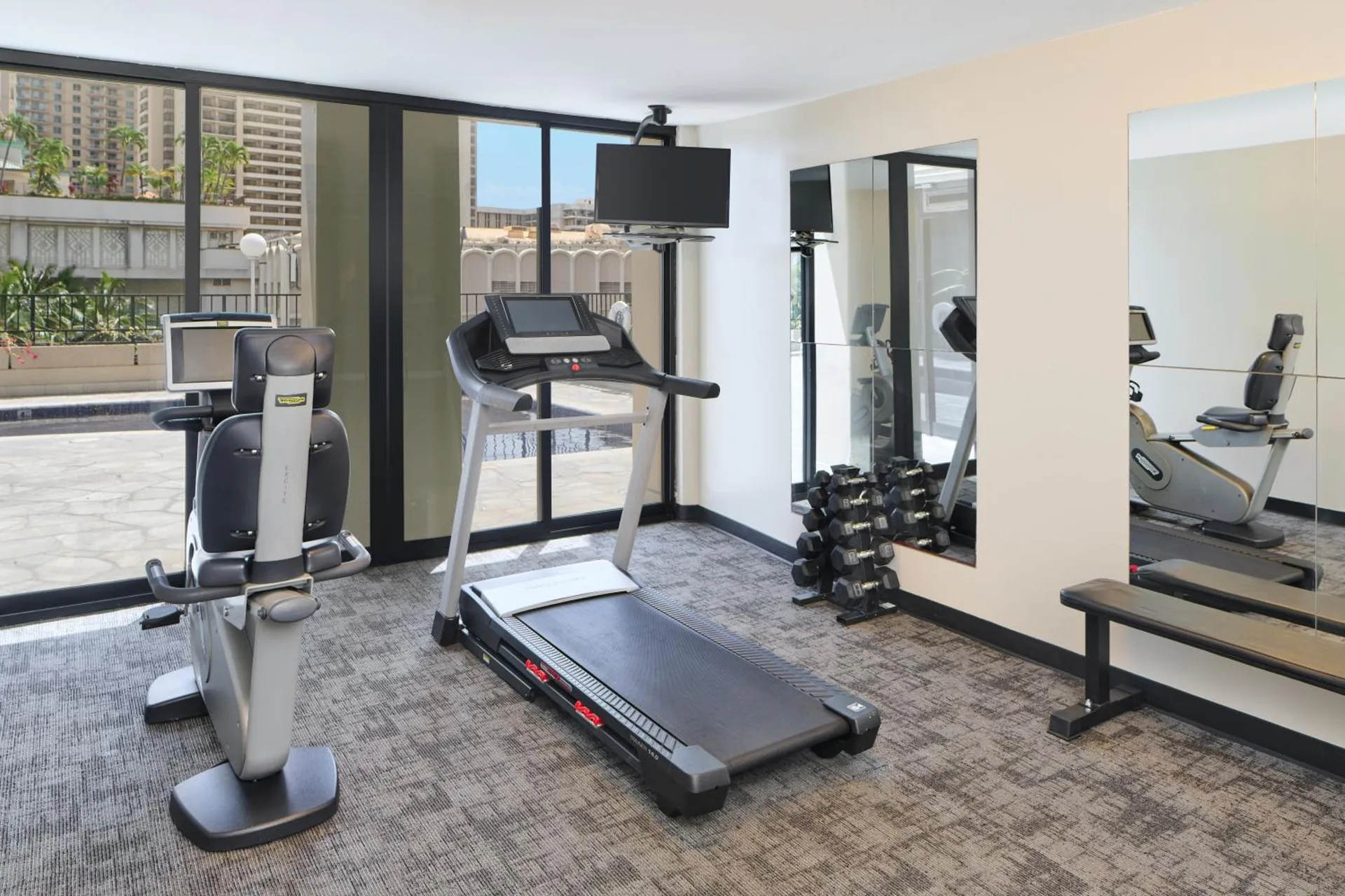 Fitness room with treadmill, recumbent bike and dumbbells at Aqua Palms Waikiki.