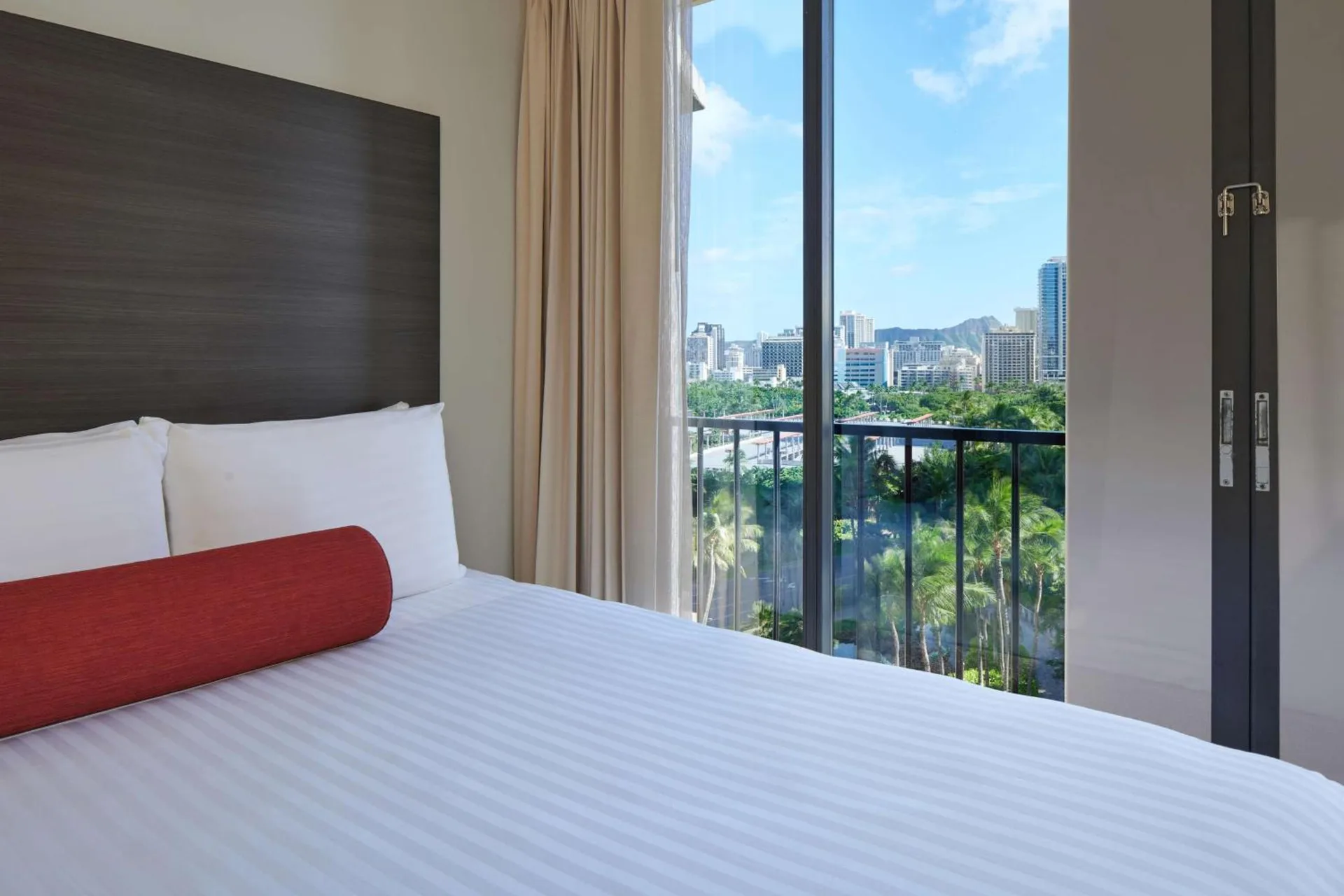 King bed beside sliding glass doors with a Waikiki city view at Aqua Palms Waikiki.
