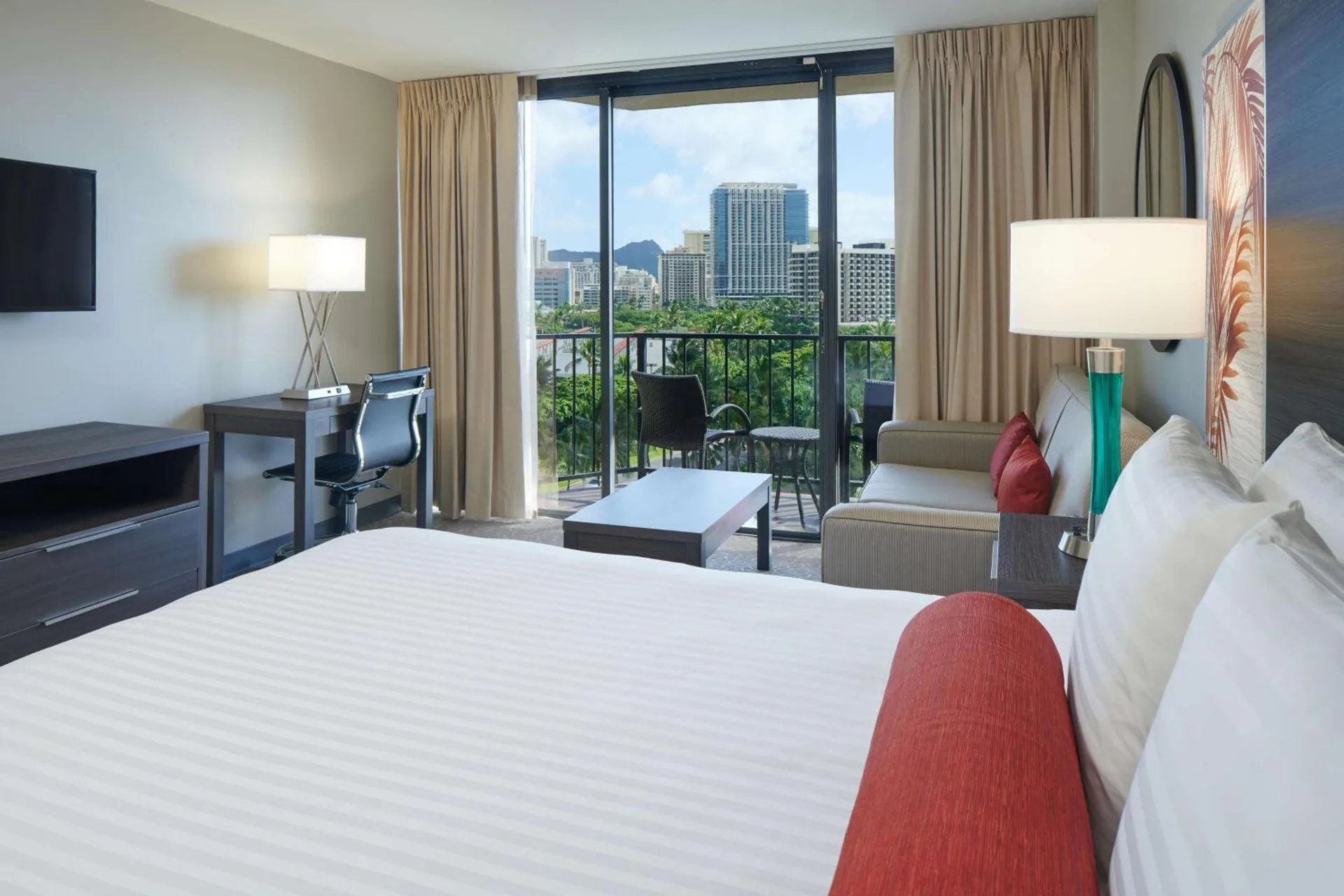 Guest room with king bed, sofa, desk and balcony city view at Aqua Palms Waikiki.