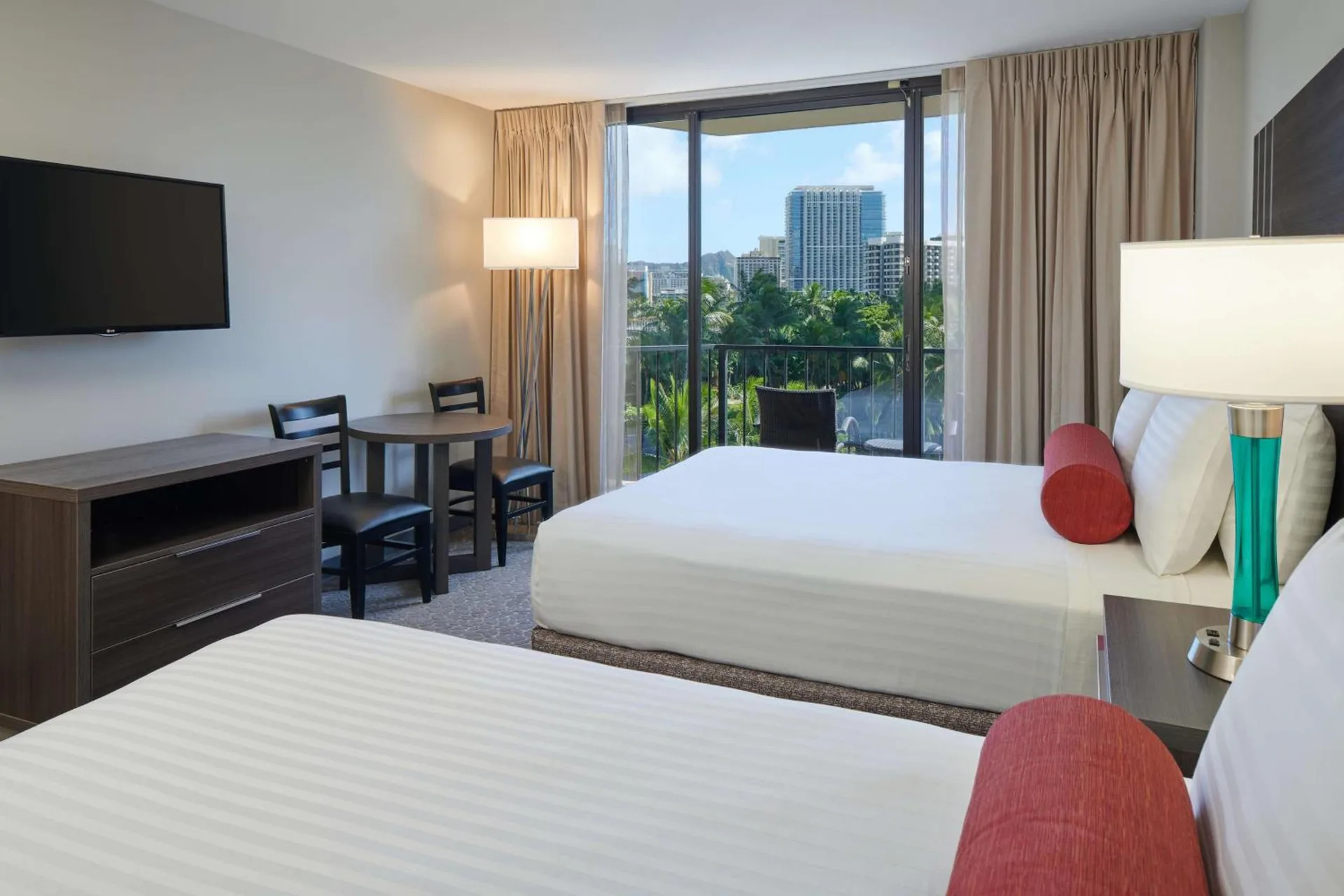 Guest room with two beds, desk, TV, and balcony view at Aqua Palms Waikiki.