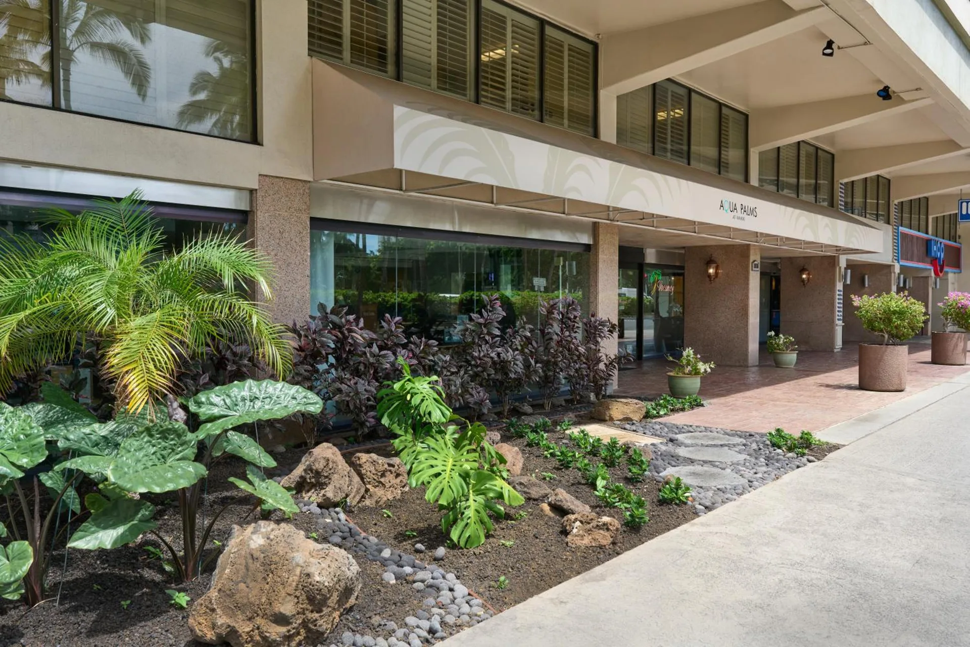 Hotel entrance with tropical landscaping and walkway at Aqua Palms Waikiki.