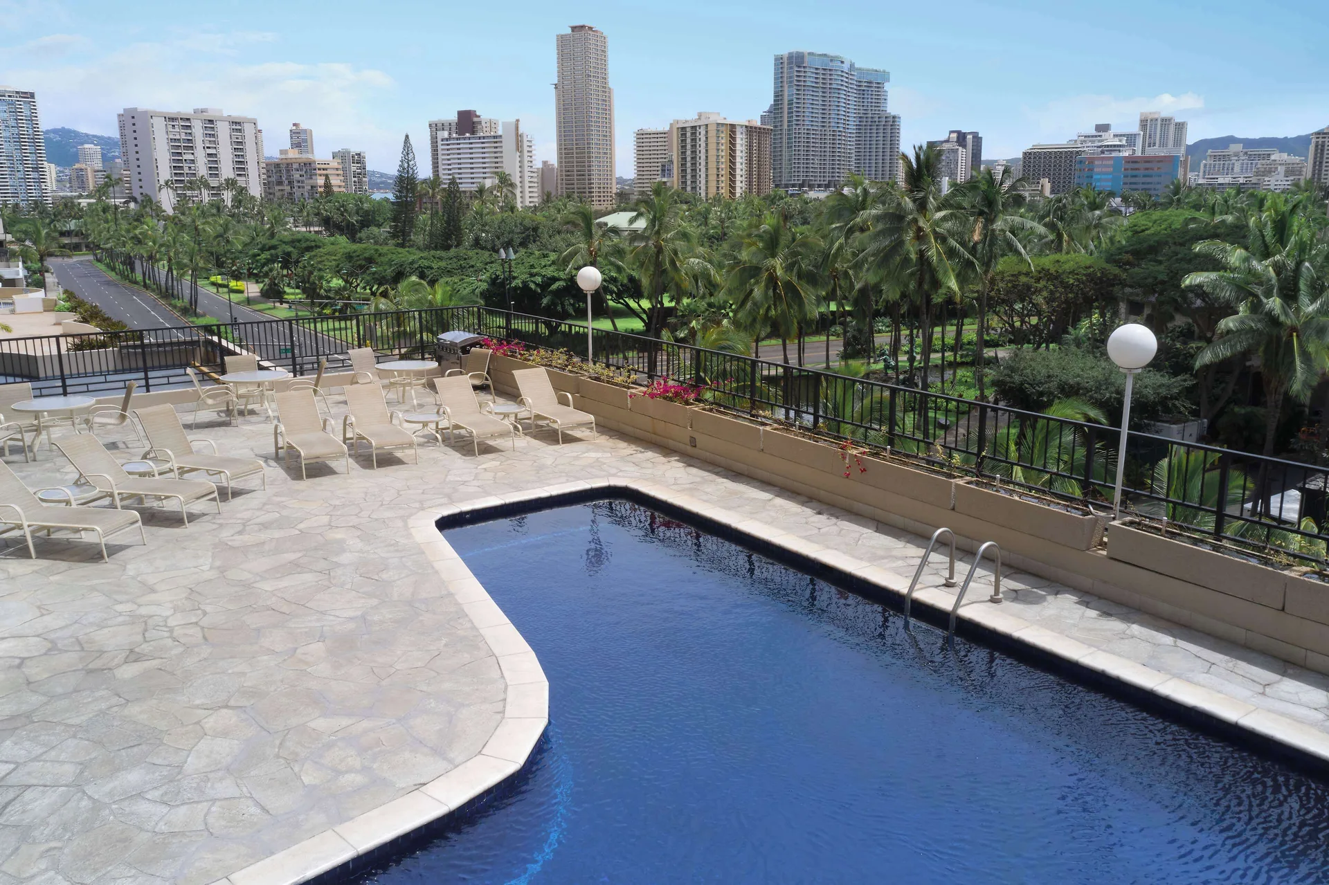 Outdoor pool deck with lounge chairs and city views at Aqua Palms Waikiki.