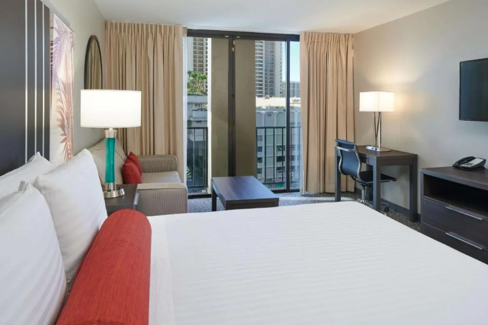 City View guest room with king bed, balcony, desk, and sofa at Aqua Palms Waikiki.