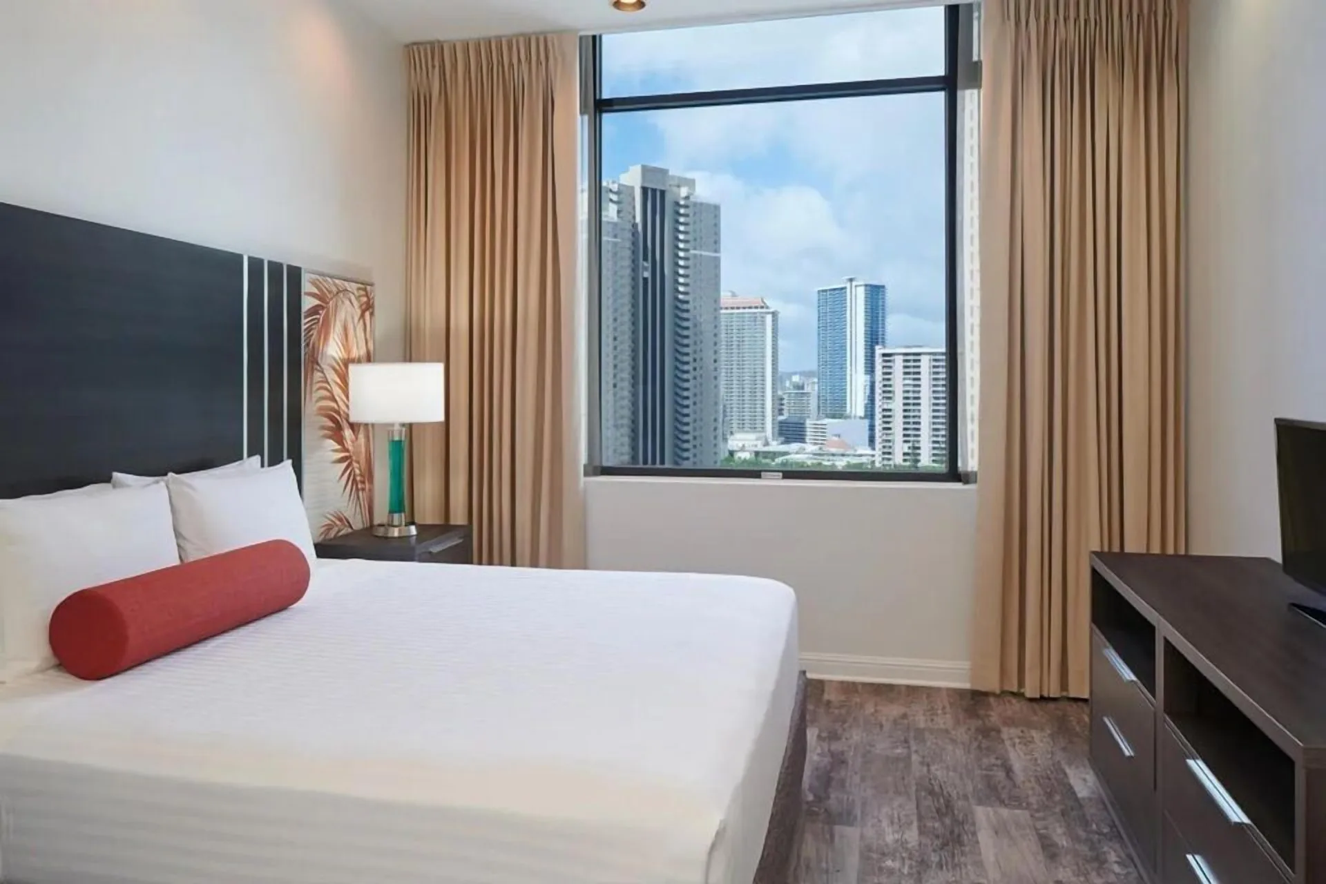 Luxury Suite bedroom with king bed and city-view window at Aqua Palms Waikiki.
