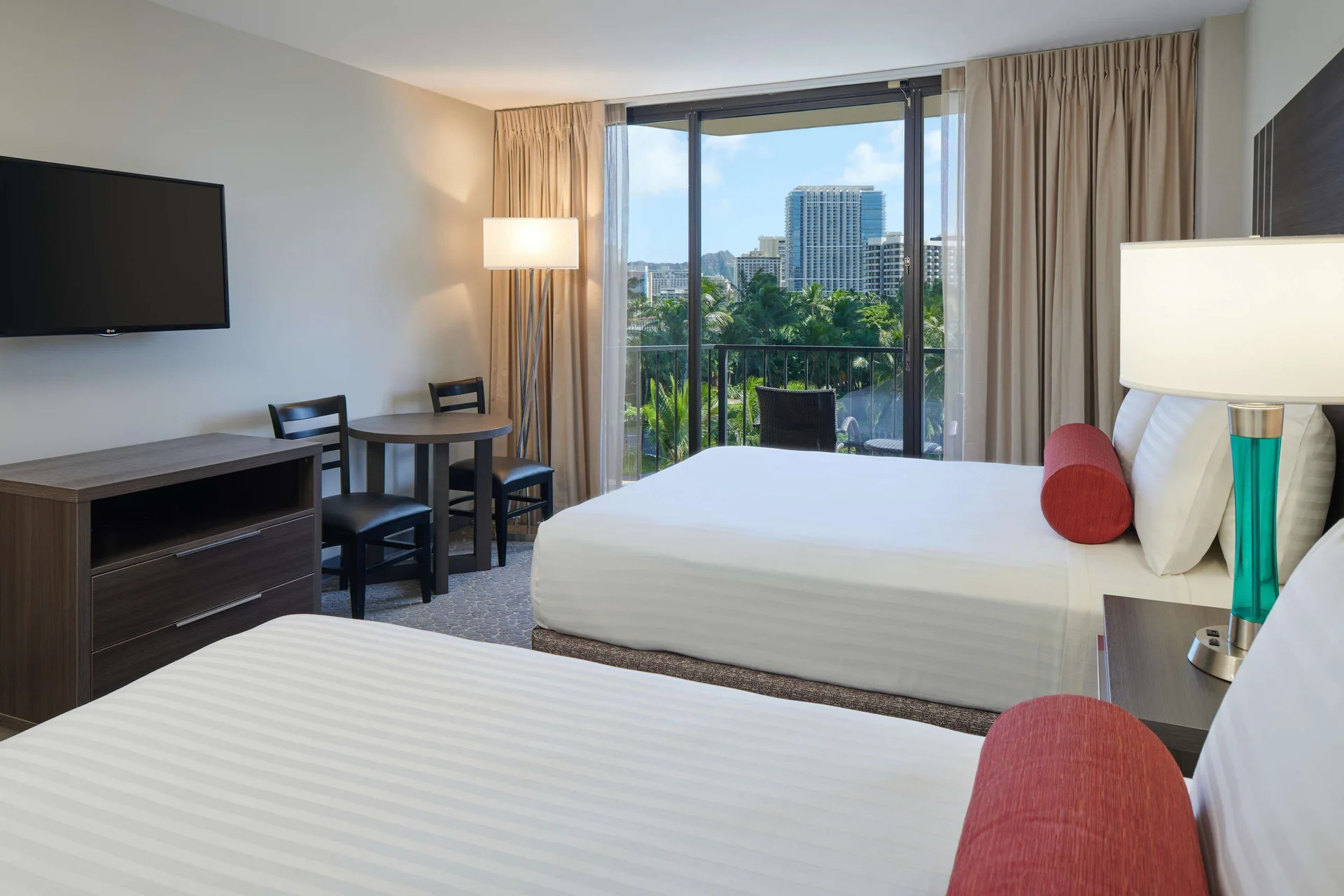 City View room with two beds, TV, dining table and balcony at Aqua Palms Waikiki.