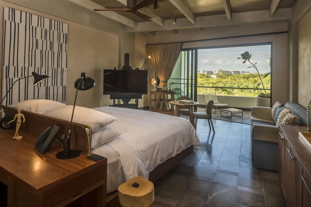 Guest room with king bed and balcony view at Atelier Playa Mujeres.