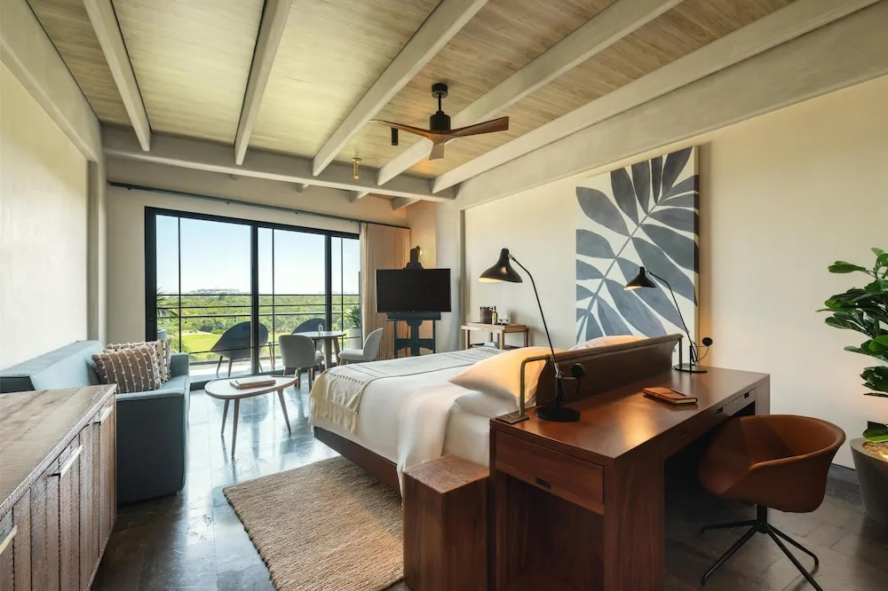 King bed guest room with desk and balcony view at Atelier Playa Mujeres.