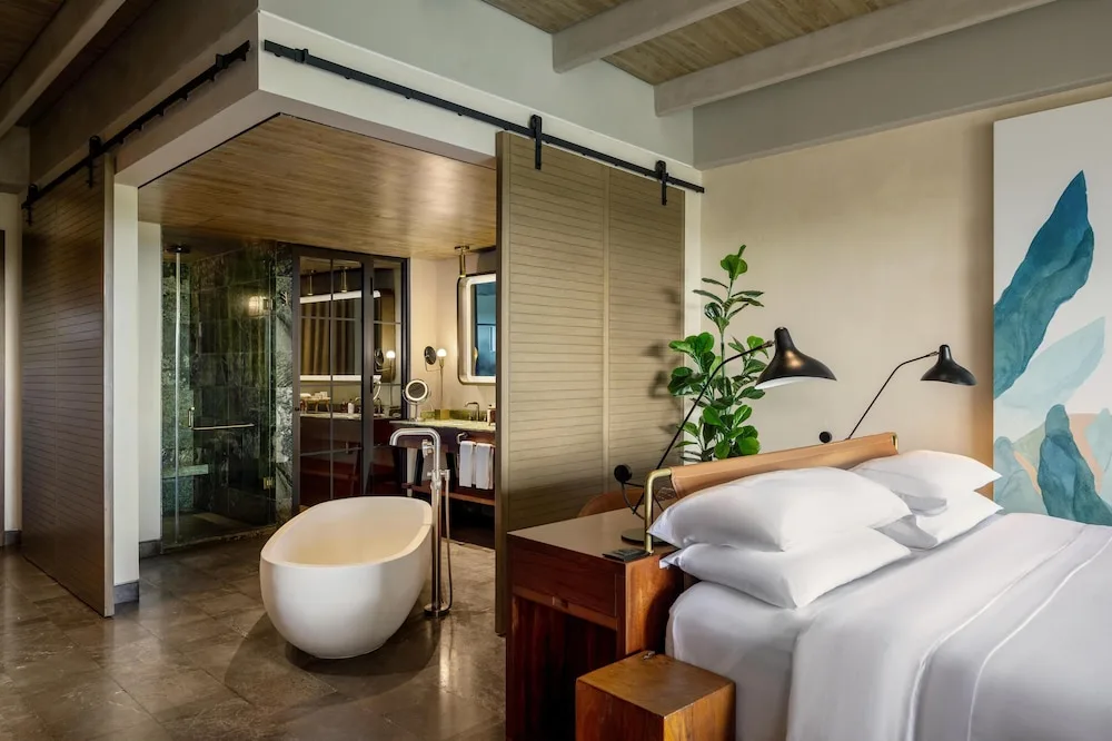King bed guest room with freestanding tub and open bathroom at Atelier Playa Mujeres.