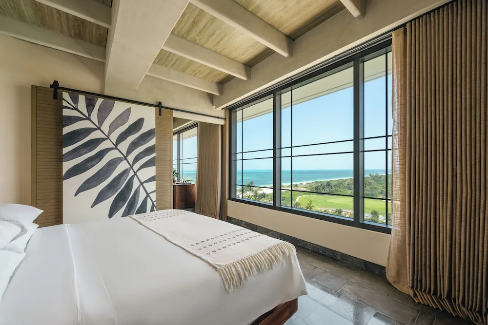 King bed guest room with wide ocean-facing windows at Atelier Playa Mujeres.