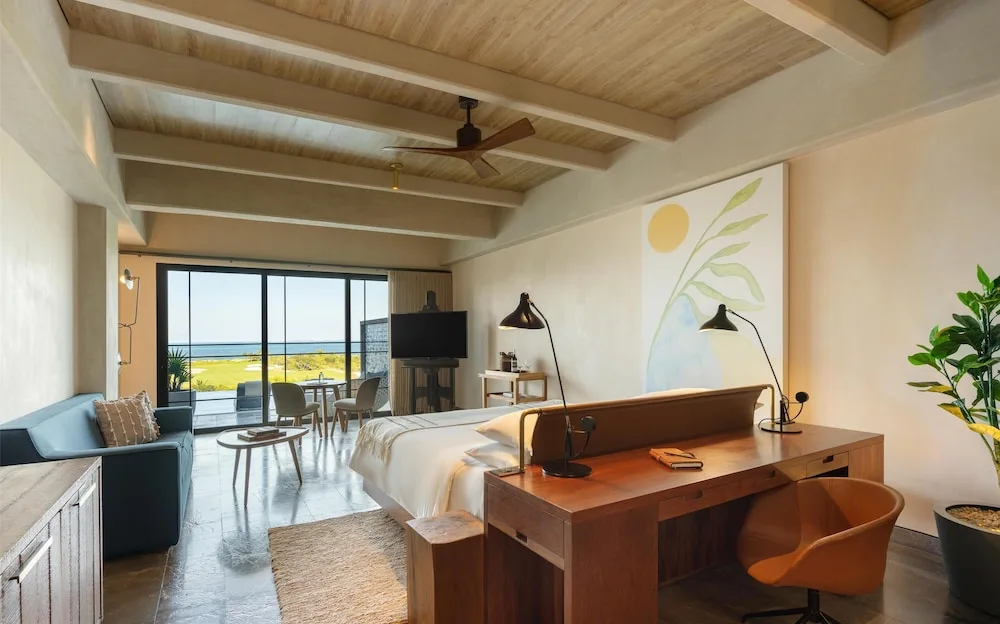 King bed guest room with desk, sofa, and water view at Atelier Playa Mujeres.
