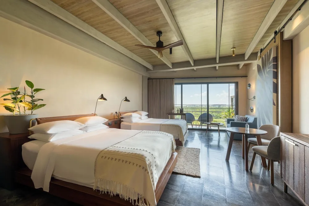 Two queen beds in a guest room with sitting area at Atelier Playa Mujeres.