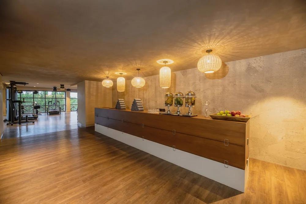 Gym refreshment counter with towels, fruit, and drinks at Atelier Playa Mujeres.