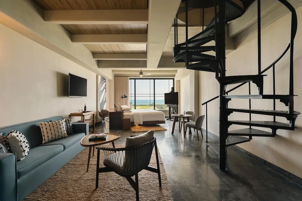Loft-style king bed suite with living area and spiral staircase at Atelier Playa Mujeres.