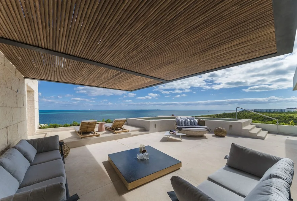 Large ocean-view terrace with sofas and lounge chairs at Atelier Playa Mujeres.