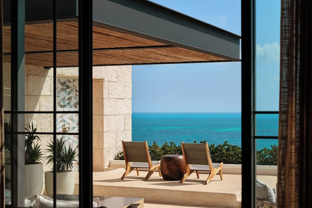 Terrace lounge chairs facing the turquoise sea at Atelier Playa Mujeres.