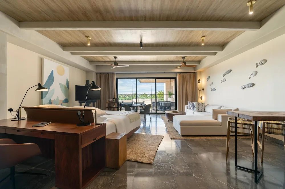 Open-plan suite with king bed, sofa, dining table, and terrace at Atelier Playa Mujeres.