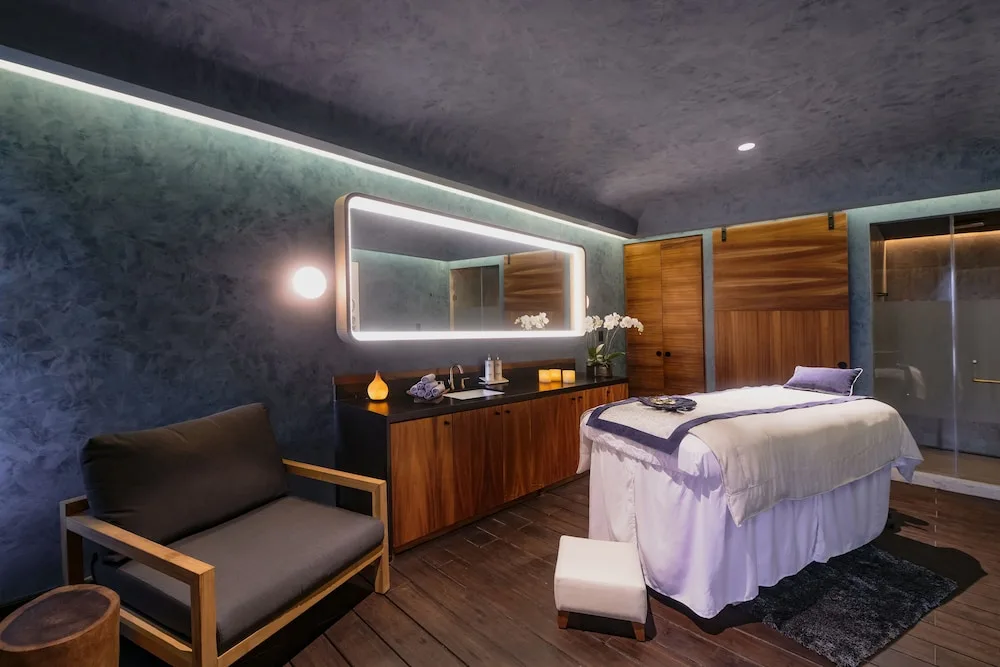 Private spa treatment room with massage table and lit mirror at Atelier Playa Mujeres.