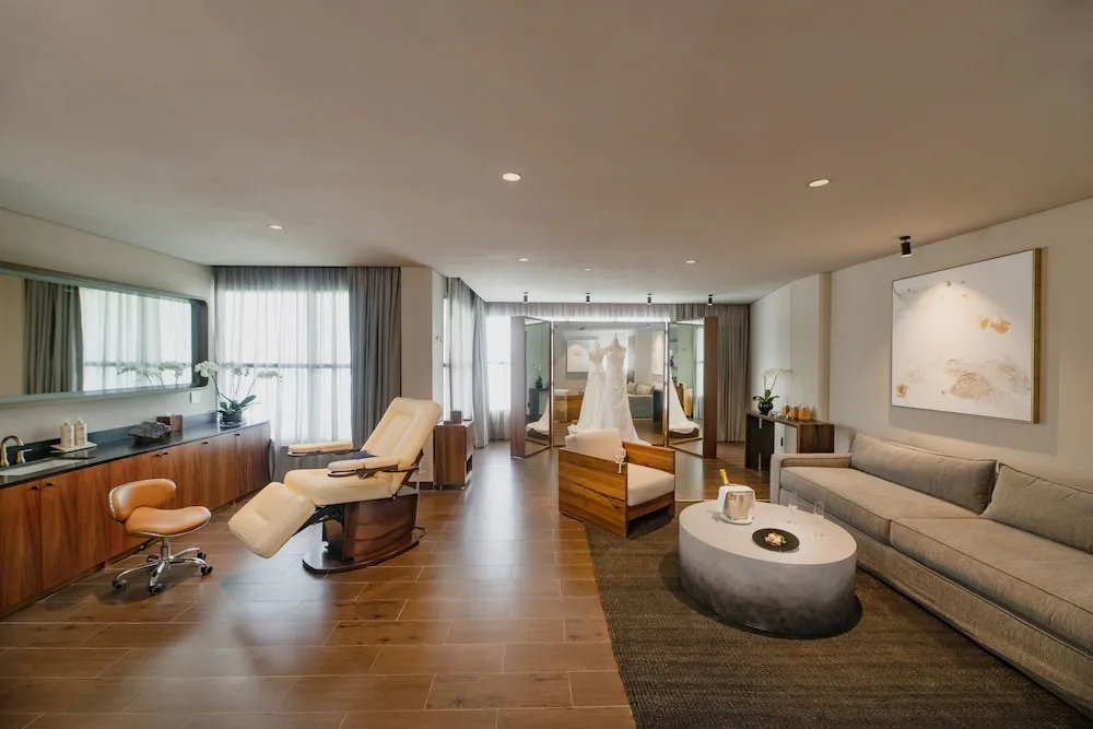 Spa treatment lounge with a recliner, sofa and bridal dress at Atelier Playa Mujeres.
