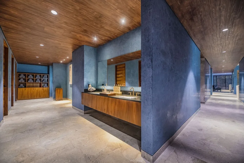 Spa vanity area with blue walls and wood accents at Atelier Playa Mujeres.