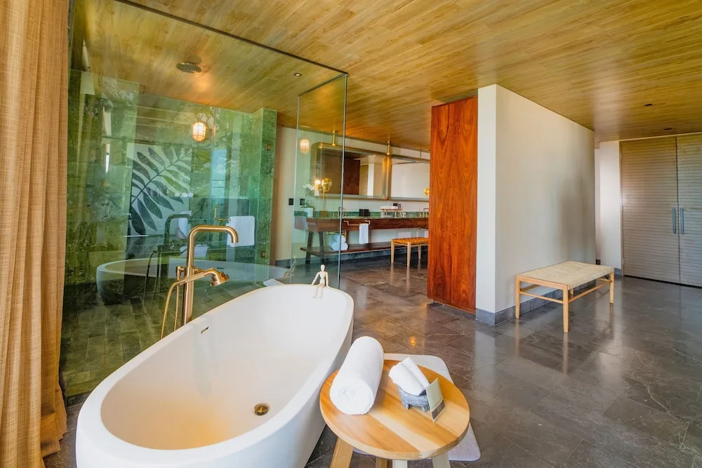 Suite bathroom with freestanding tub and glass shower at Atelier Playa Mujeres.