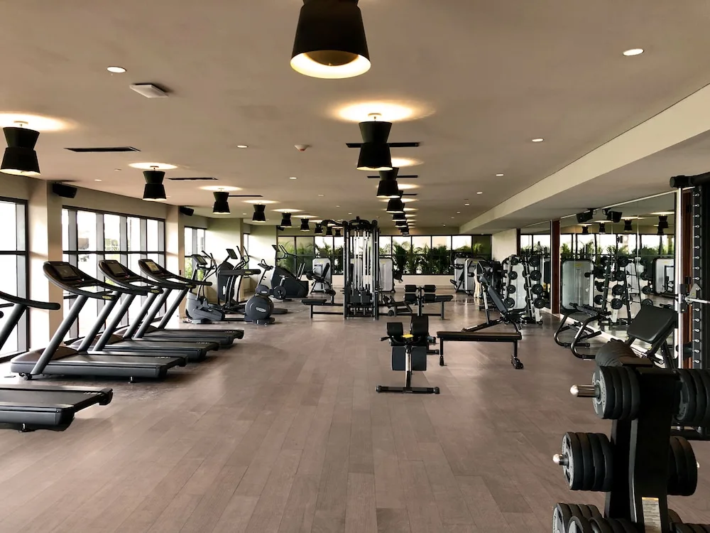 Wide fitness center with cardio machines and weight benches at Atelier Playa Mujeres.