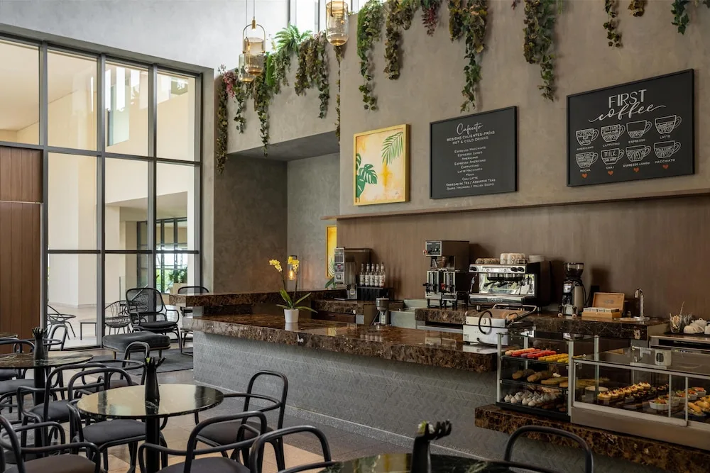 Coffee counter with café tables and pastry cases at Atelier Playa Mujeres.