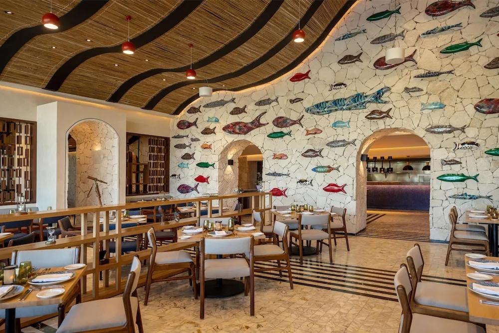 Dining room with fish-covered stone wall at Atelier Playa Mujeres.