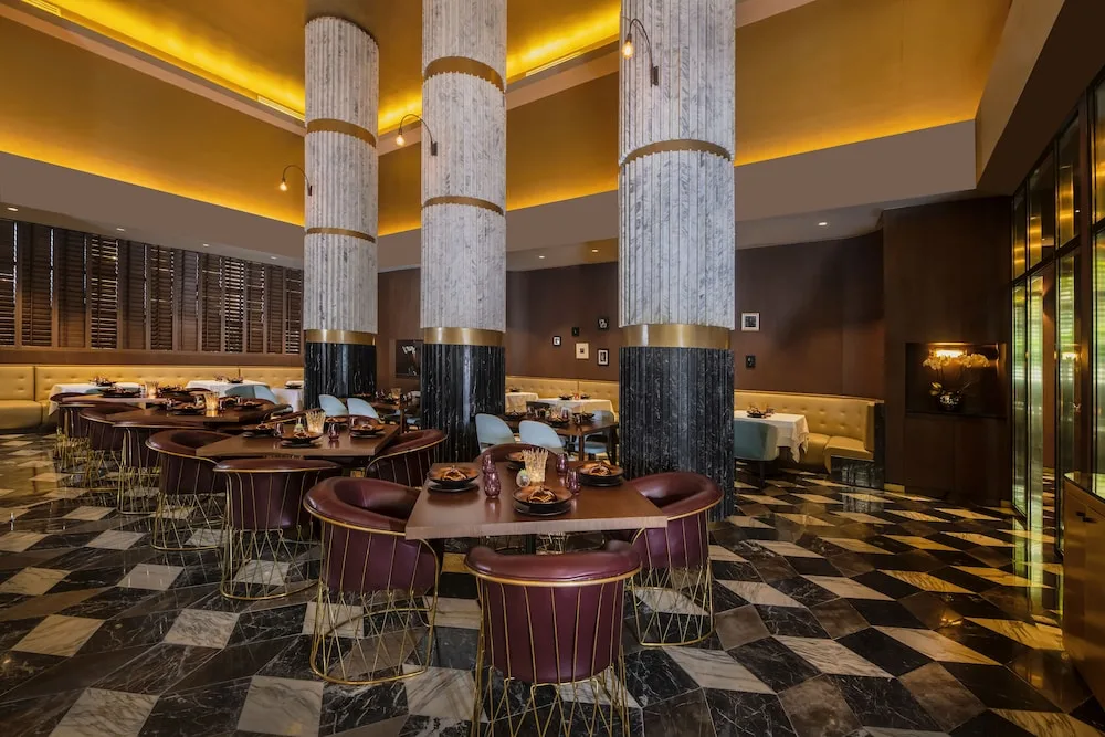 Elegant restaurant dining room with round tables and marble columns at Atelier Playa Mujeres.
