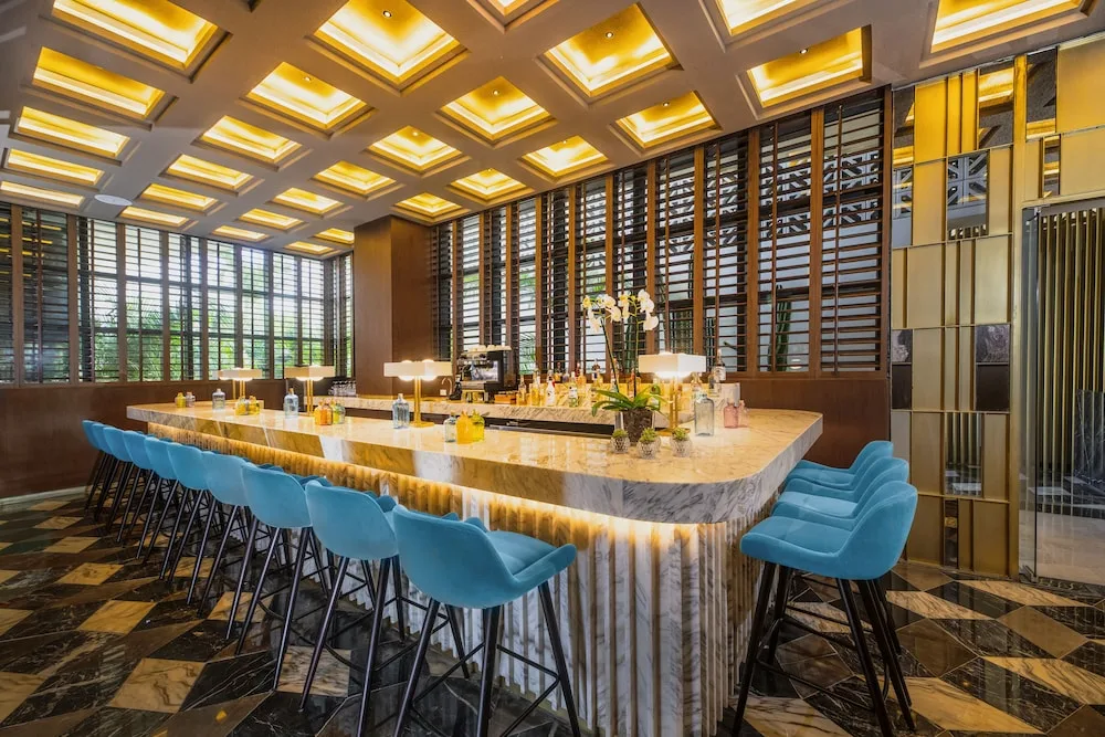 Bright marble bar with blue stools and backlit ceiling panels at Atelier Playa Mujeres.
