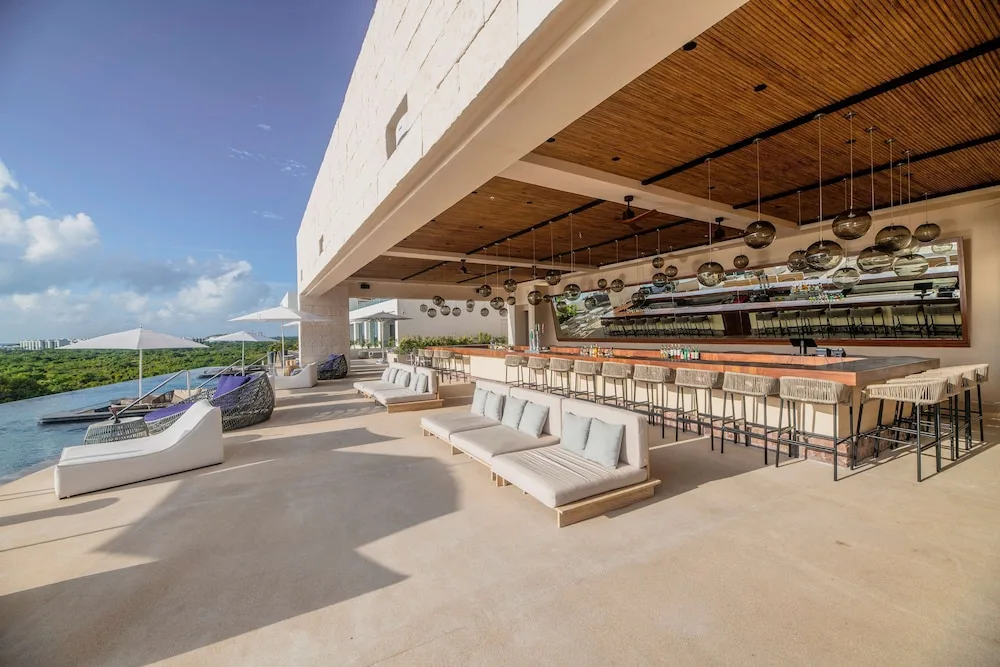 Open-air rooftop bar with counter seating beside the pool at Atelier Playa Mujeres.