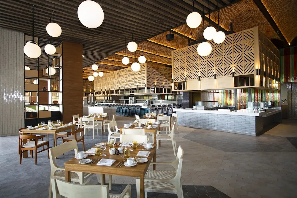 Bright restaurant dining room with open kitchen at Atelier Playa Mujeres.