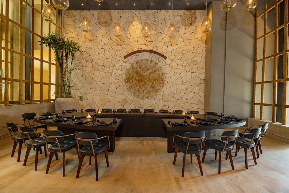 Private dining room with stone wall and pendant lights at Atelier Playa Mujeres.