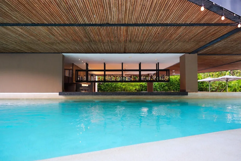 Swim-up pool bar beneath a wood ceiling at Atelier Playa Mujeres.