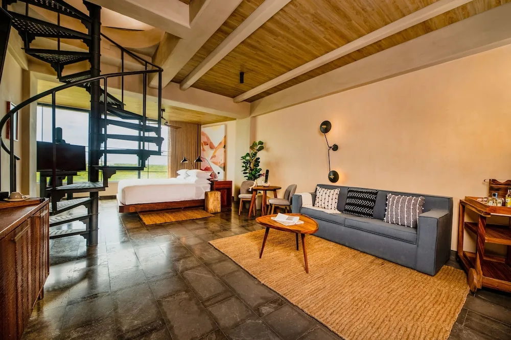 Inspira Rooftop Suite living area, spiral stair and bed at Atelier Playa Mujeres.