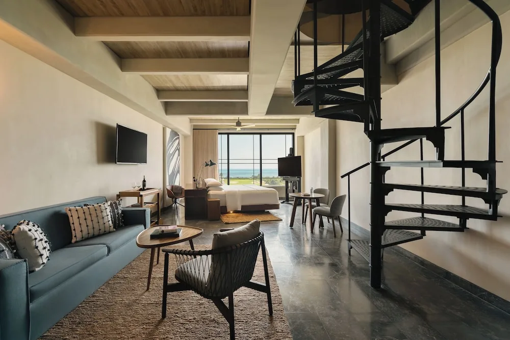 Inspira Rooftop Suite at Atelier Playa Mujeres with spiral staircase, lounge area, king bed, and panoramic Caribbean Sea views from the private rooftop.