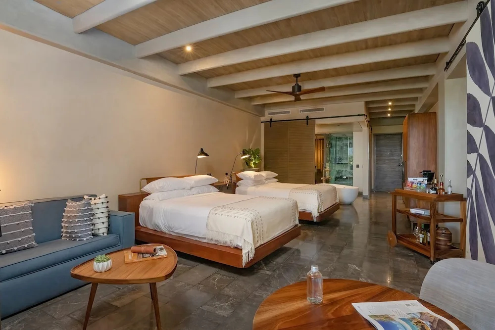 Inspira Terrace Suite with two beds, sofa, and open bath area at Atelier Playa Mujeres.