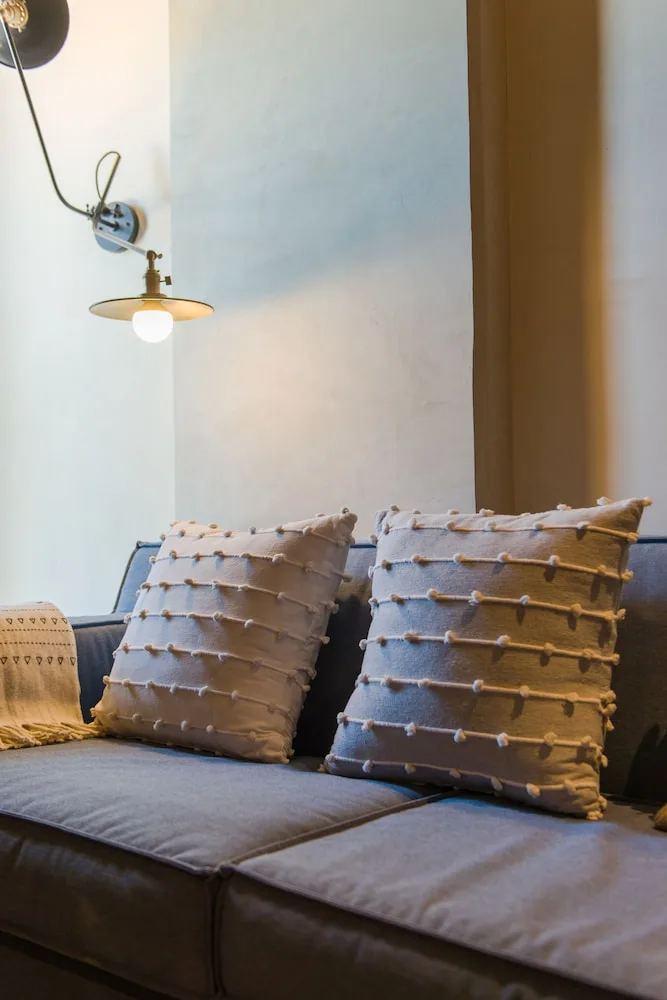 Junior Suite sofa with textured pillows and wall lamp at Atelier Playa Mujeres.